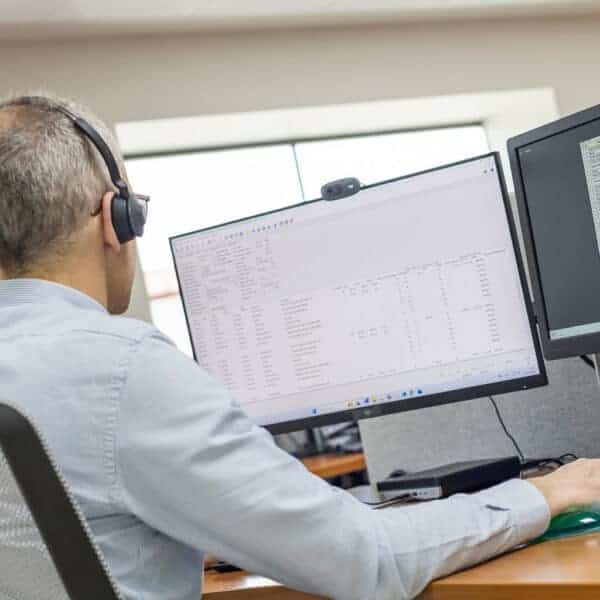 Profesional trabajando en diseño de armario eléctrico con doble monitor y software especializado.