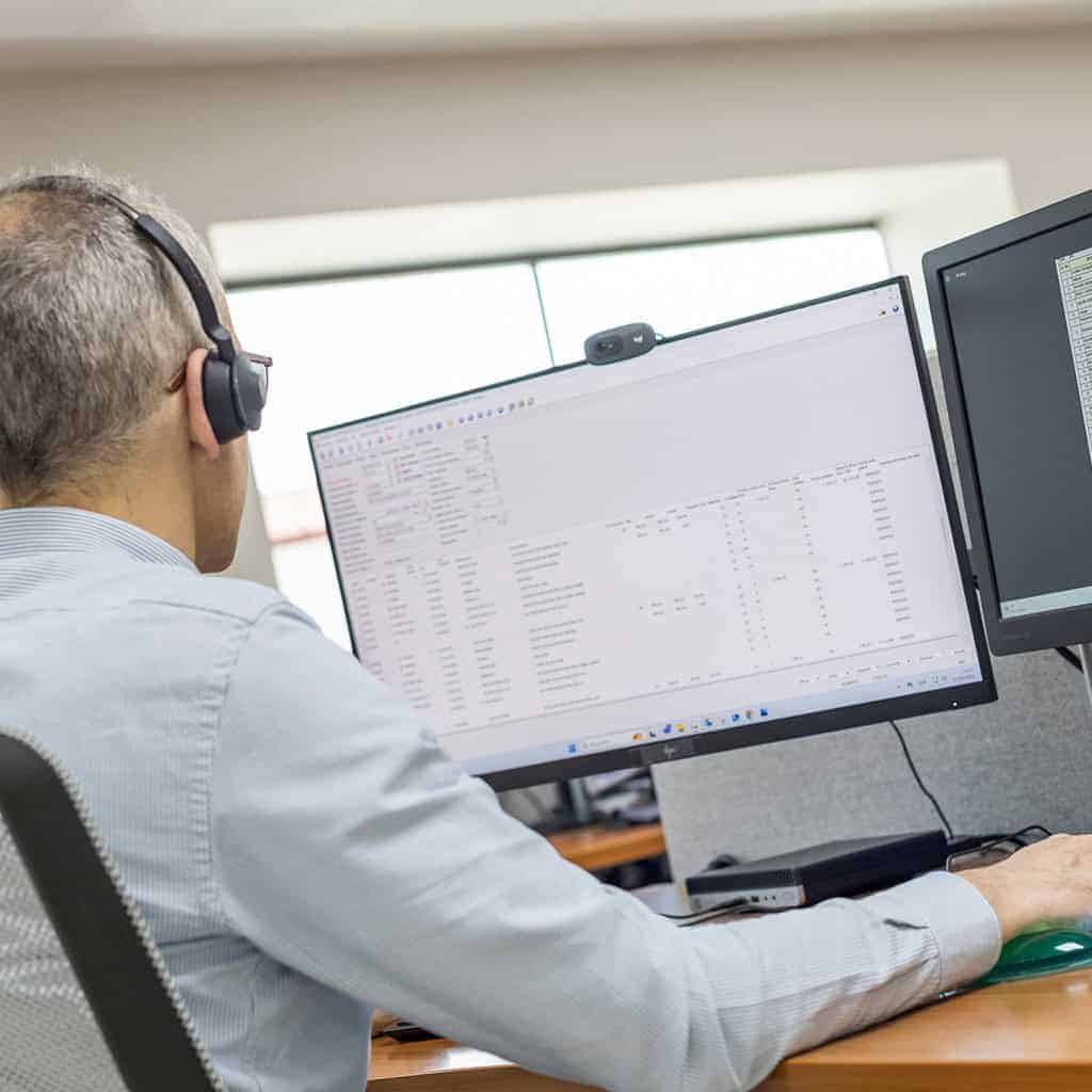 Profesional trabajando en diseño de armario eléctrico con doble monitor y software especializado.